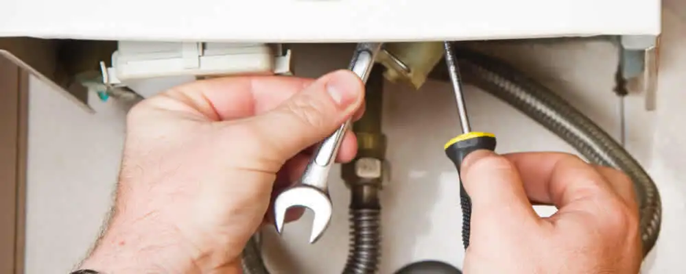 Boiler repair technician tightening pipe fittings and connections in Miami, FL