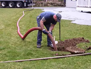 Septic pumping technician servicing a residential septic tank with a vacuum hose in Miami, FL