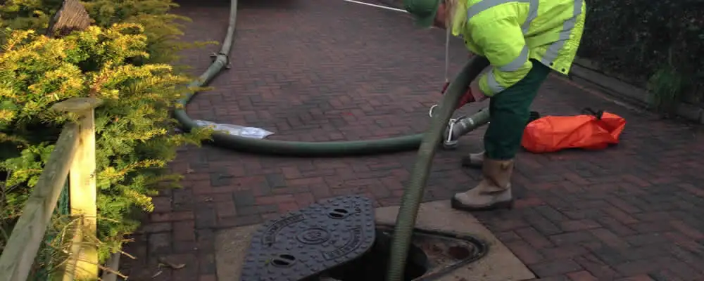 Septic tank cleaning technician servicing a septic tank with a vacuum hose in Miami, FL