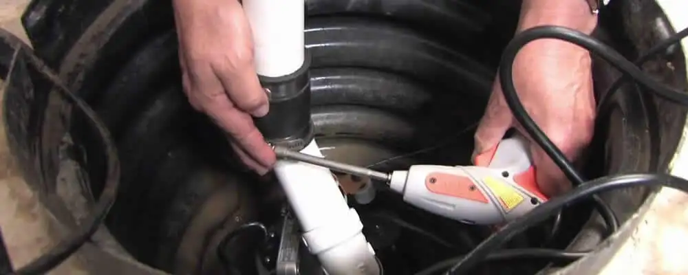 Sump pump installation technician connecting PVC discharge piping in Miami, FL