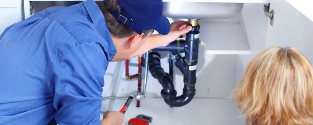 Plumber repairing under-sink drain pipes and fittings in Miami, FL