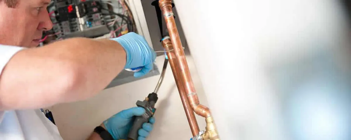 Water heater repair technician testing copper pipe connections and controls in Miami, FL